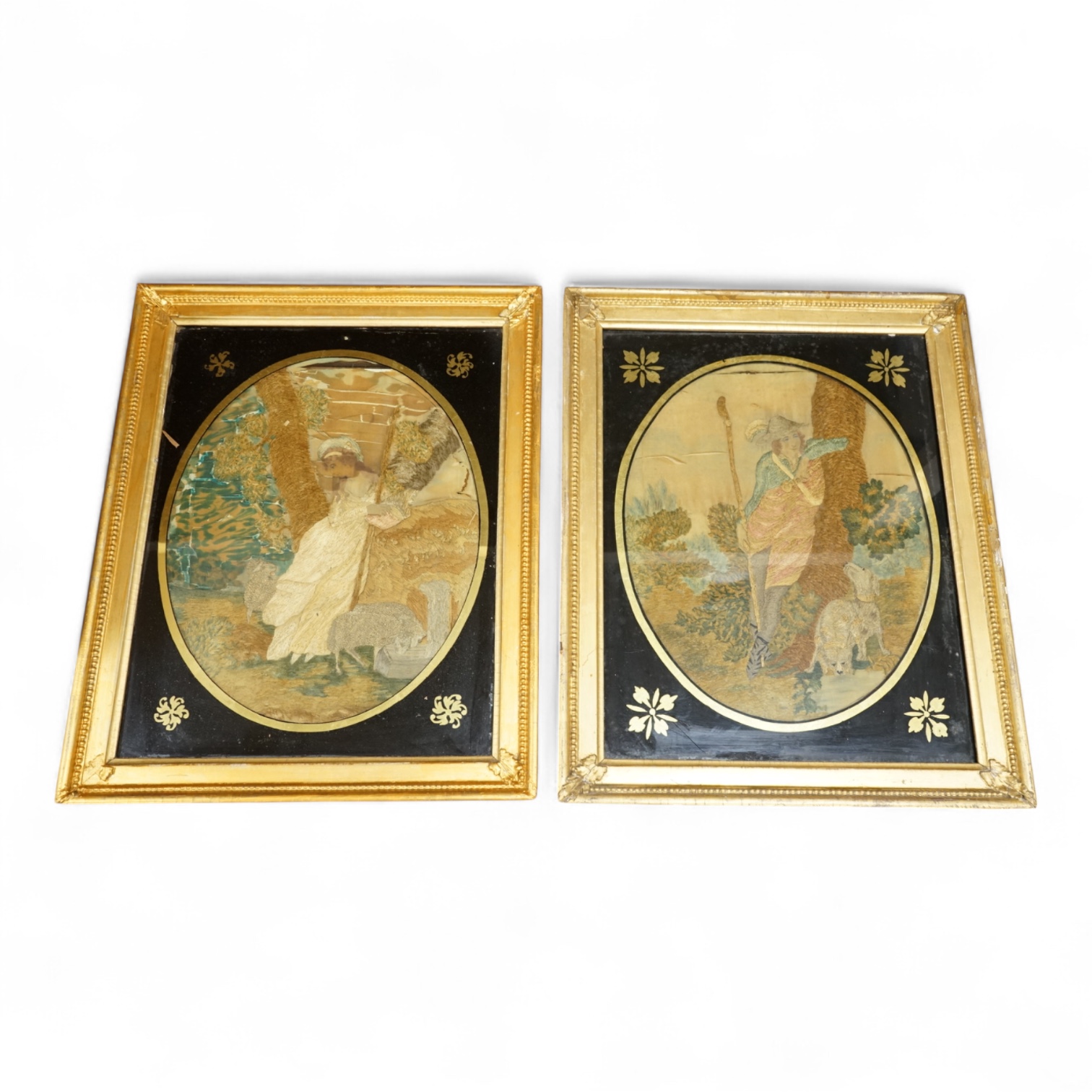 A pair of oval framed early 19th century silk embroideries of a Shepherd and Shepherdess mounted in Verre eglomise glass and gilt frames. Embroideries 28cm high